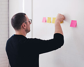 Man placing post-it notes on whiteboard